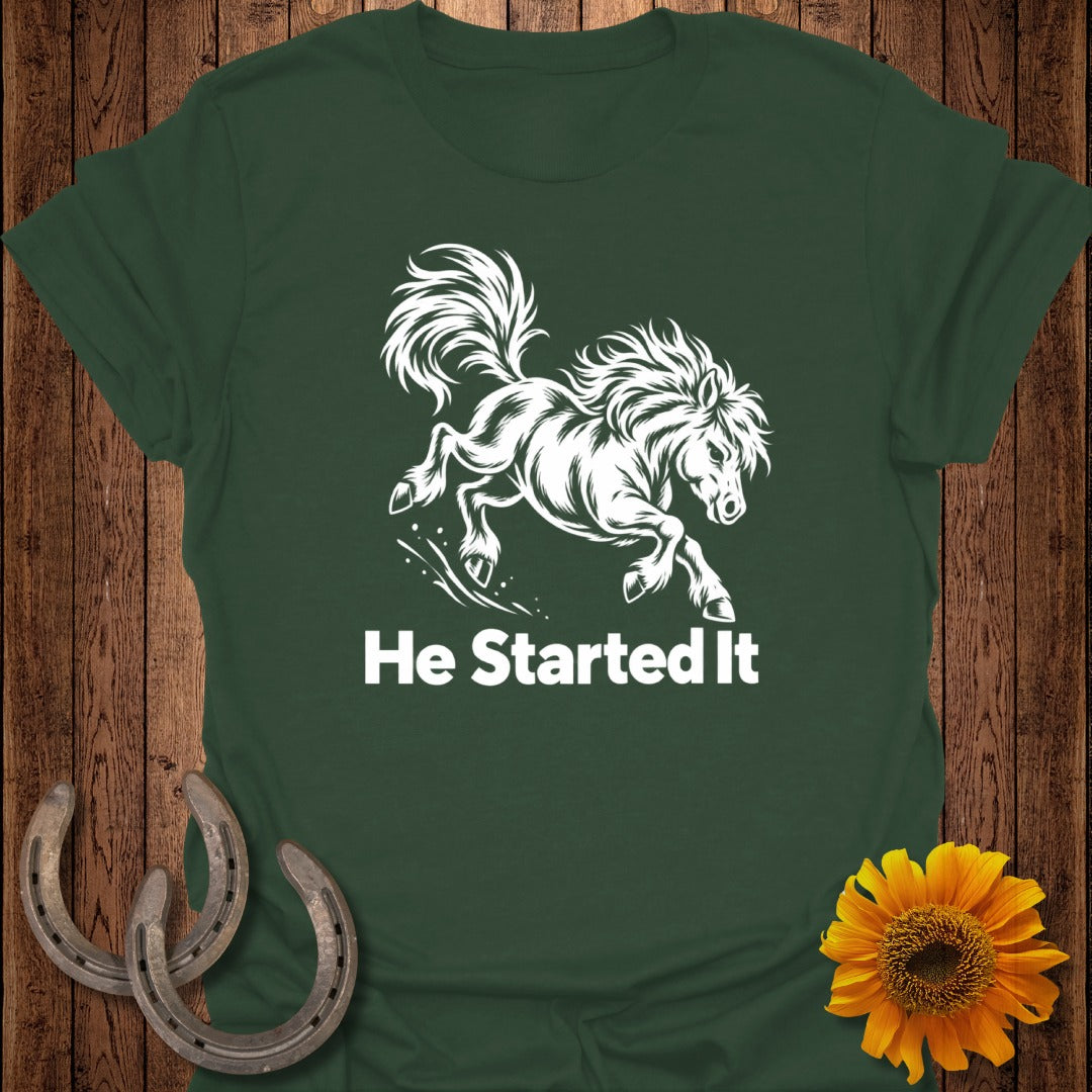 Green t-shirt with white graphic of a running horse and text "He Started It".