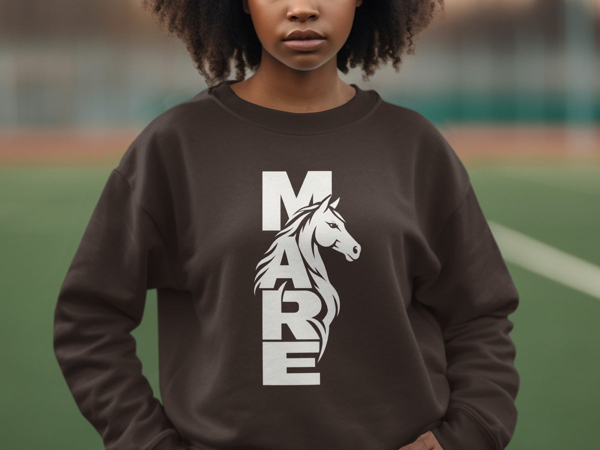 A person wearing a brown sweatshirt with a vertical white graphic spelling out the word MARE alongside a horse head.