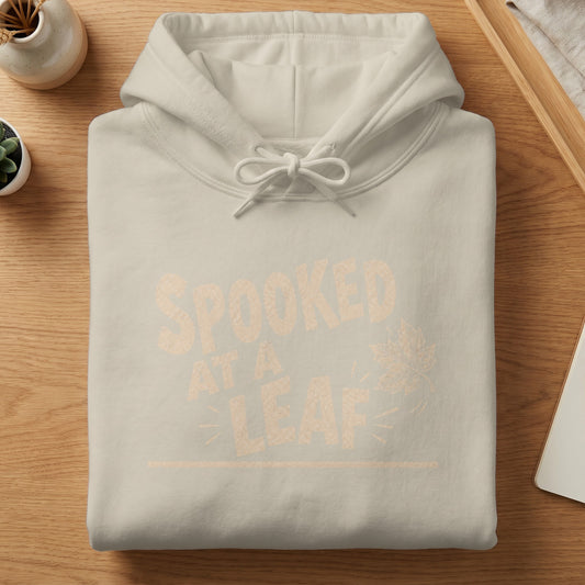 Light tan hoodie with "SPOOKED AT A LEAF" graphic and fall leaf design.