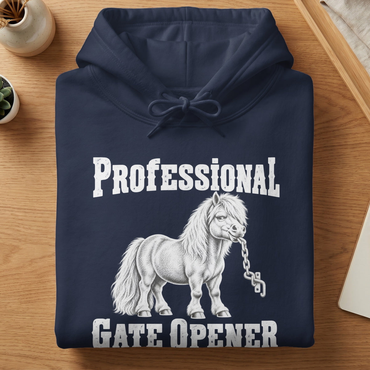 Folded navy blue hoodie featuring a white illustration of a pony biting a chain with text reading PROFESSIONAL GATE OPENER.