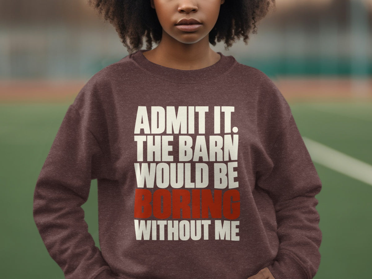A person with curly dark hair wears a brown crewneck sweatshirt featuring white and red text.