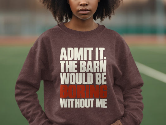 A person with curly dark hair wears a brown crewneck sweatshirt featuring white and red text.