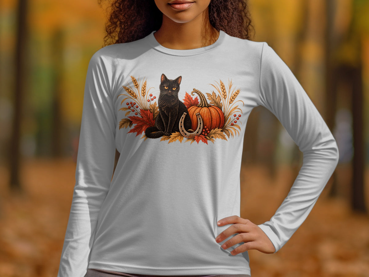 Black cat, pumpkin, horseshoe, and autumn leaves graphic on a white long-sleeve shirt.