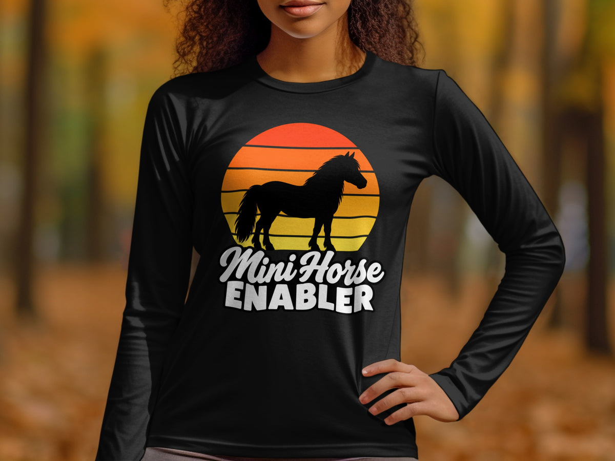 A person wearing a black long-sleeve shirt featuring a horse graphic and the text Mini Horse Enabler.
