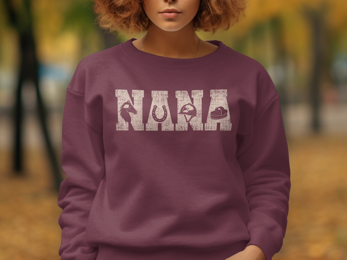 Maroon sweatshirt with "NANA" text and horse, horseshoe, helmet, and brush graphics.