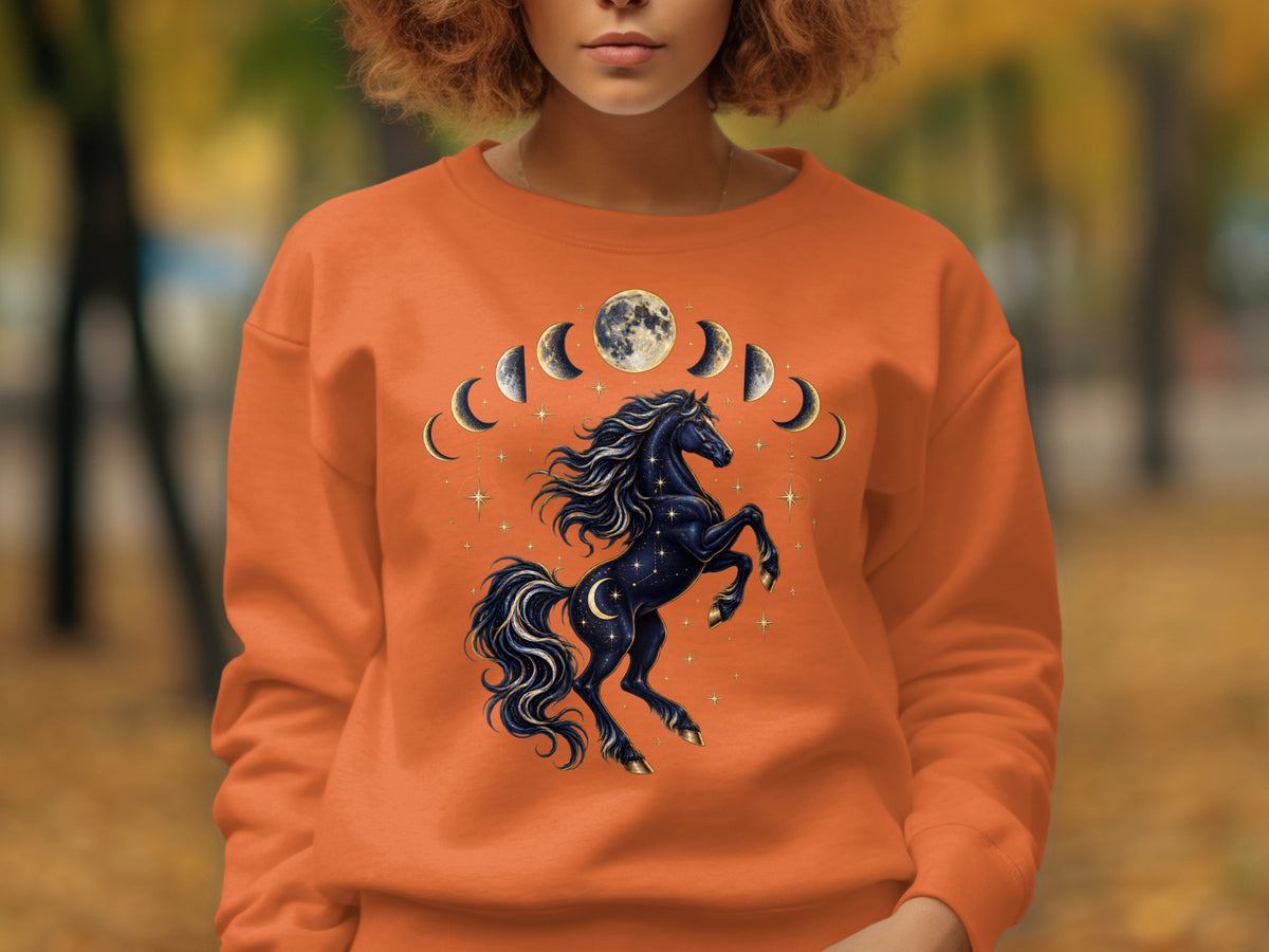 Orange sweatshirt with a black celestial horse, moon phases, and stars graphic.