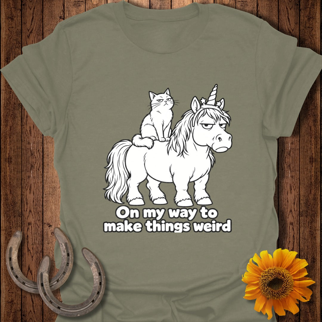 Olive green t-shirt featuring an illustration of an annoyed cat riding an equally annoyed unicorn, with text reading "On my way to make things weird".
