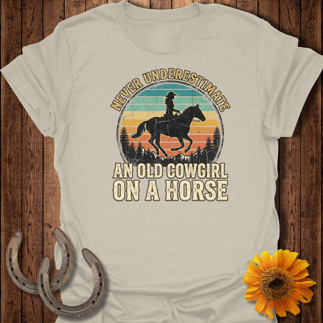 Retro distressed design of a cowgirl on a horse with text "Never Underestimate An Old Cowgirl On A Horse".