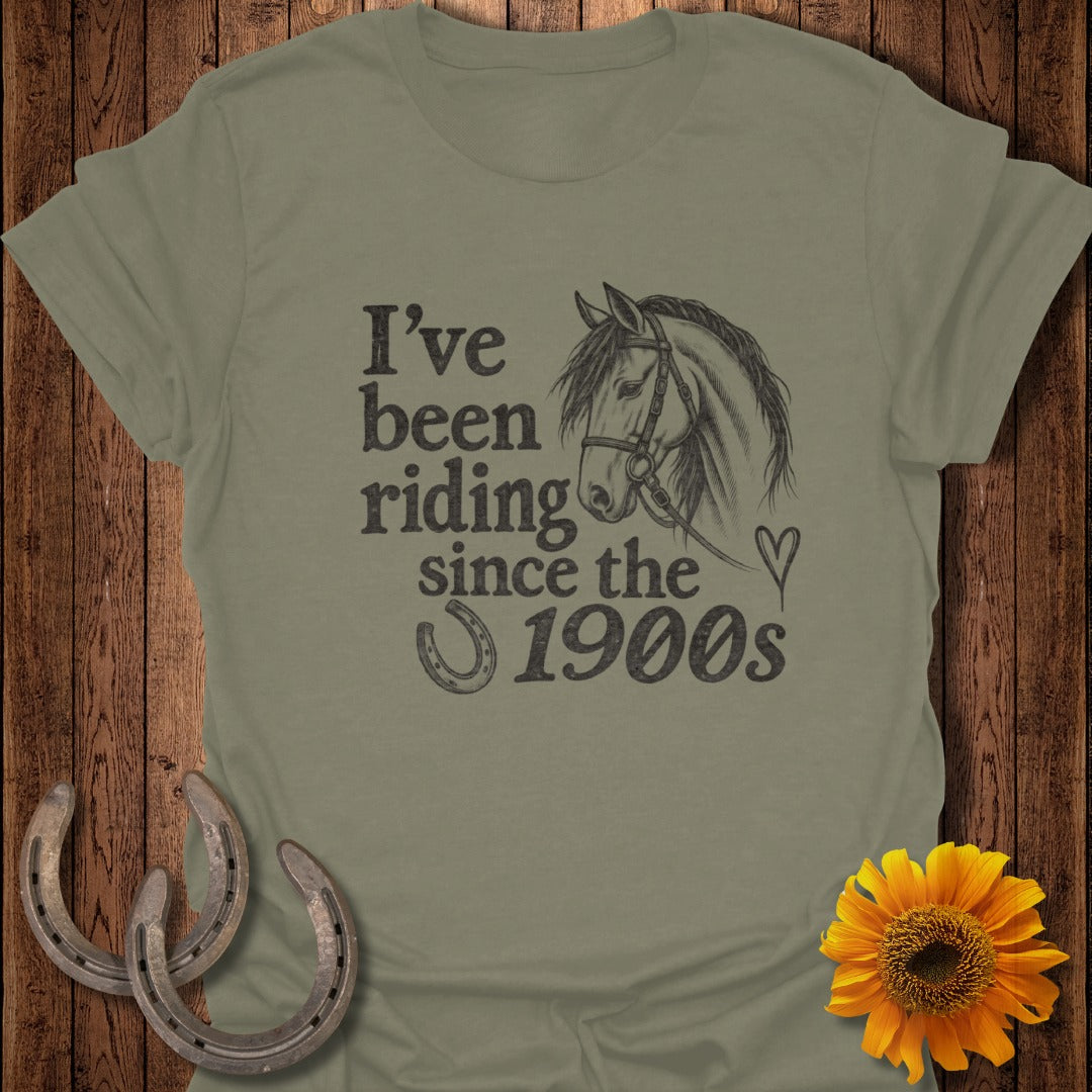 Olive green t-shirt with horse sketch and text: "I've been riding since the 1900s".