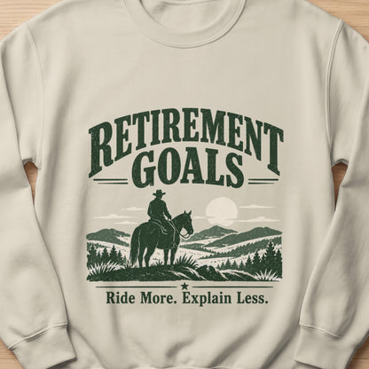 Cream sweatshirt with "Retirement Goals" and cowboy on horseback graphic.