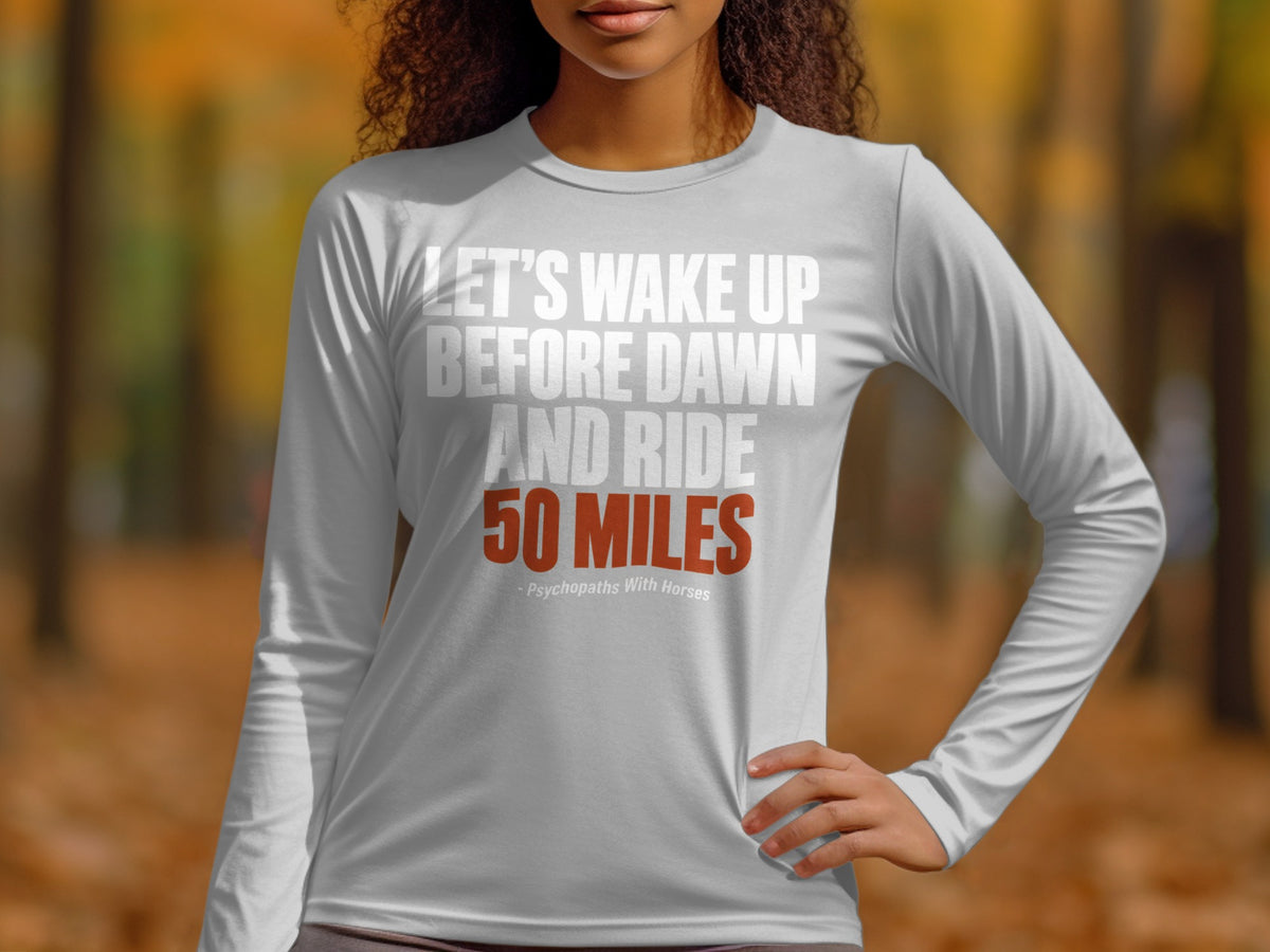 A person wearing a light gray long-sleeve shirt with the text Let's Wake Up Before Dawn And Ride 50 Miles - Psychopaths With Horses.