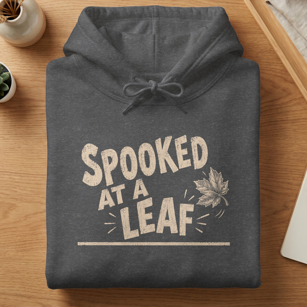 Dark grey hoodie with "Spooked At A Leaf" text and a leaf graphic.