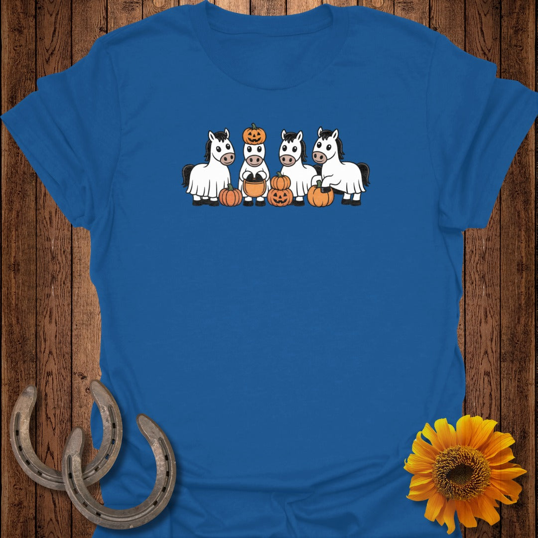 Four white horses dressed as ghosts with pumpkins, standing in a row.