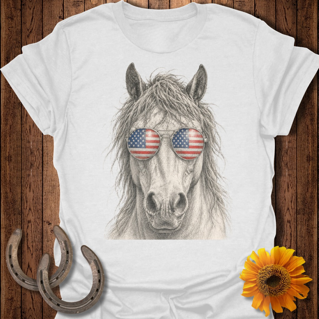 Horse wearing American flag sunglasses on white t-shirt with rustic wood and horseshoe background.