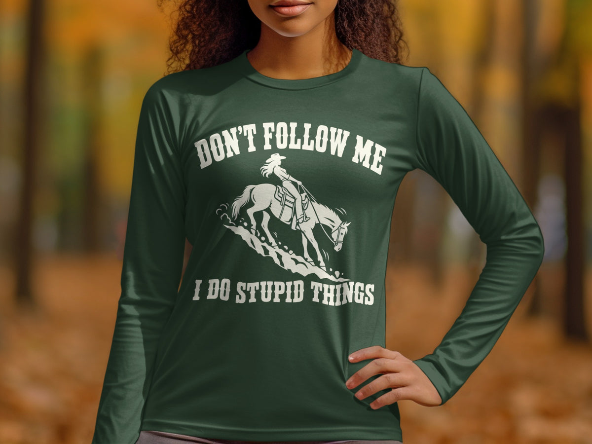 A person wearing a dark green long-sleeved shirt with white text reading "DON'T FOLLOW ME I DO STUPID THINGS" and a graphic of a person riding a horse.