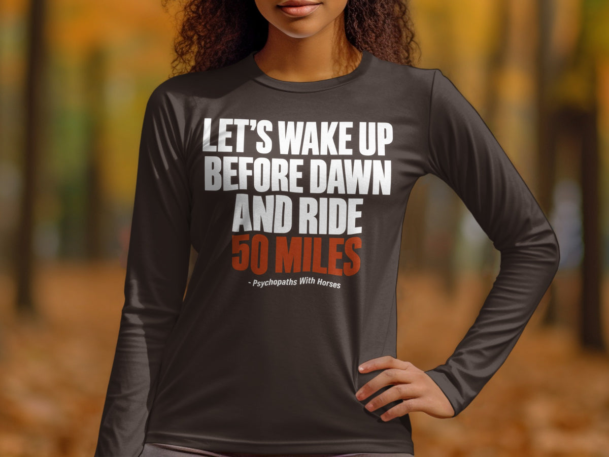 A person wears a dark gray long-sleeved shirt with the text "LET'S WAKE UP BEFORE DAWN AND RIDE 50 MILES" and "- Psychopaths With Horses" printed on the chest.