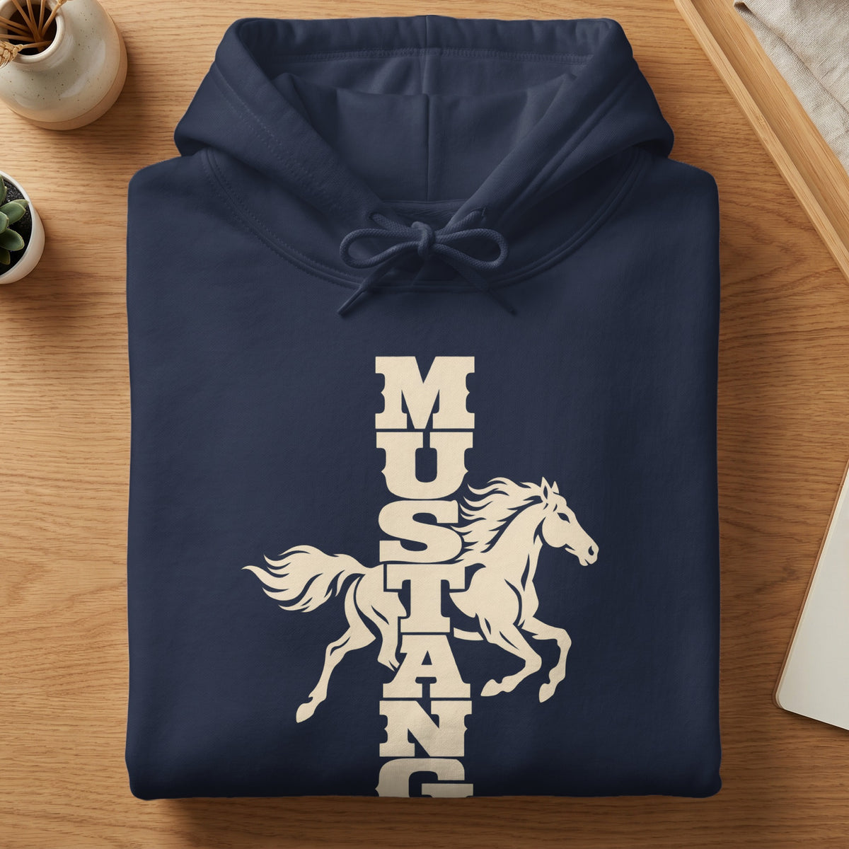 A folded dark blue hoodie with a white graphic of a running horse and vertical Mustang text on a wooden surface.