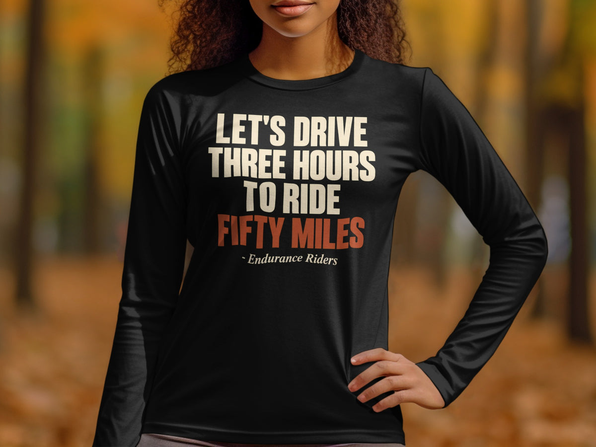 A woman wearing a black long-sleeve shirt with the text LET'S DRIVE THREE HOURS TO RIDE FIFTY MILES - Endurance Riders.