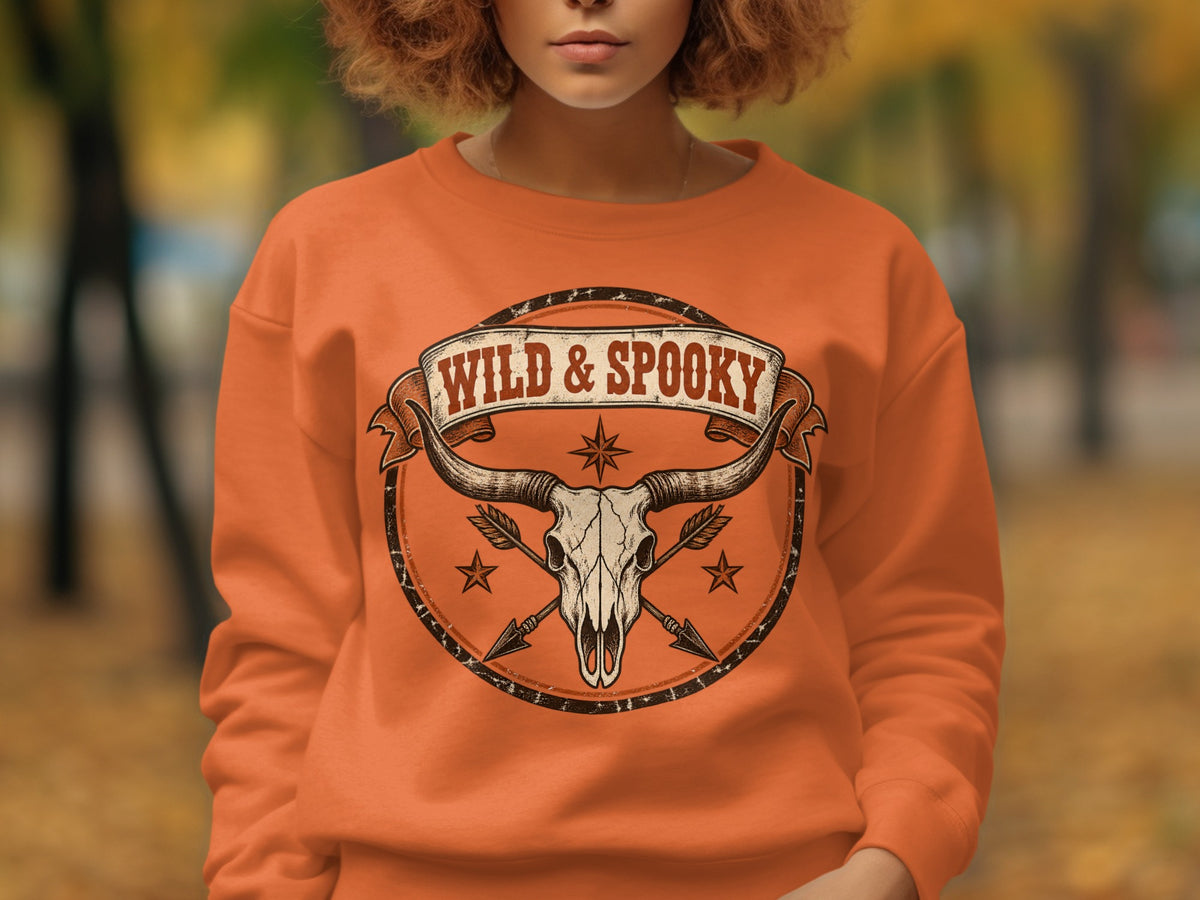 Orange sweatshirt with "Wild & Spooky" text over a longhorn skull and arrows.