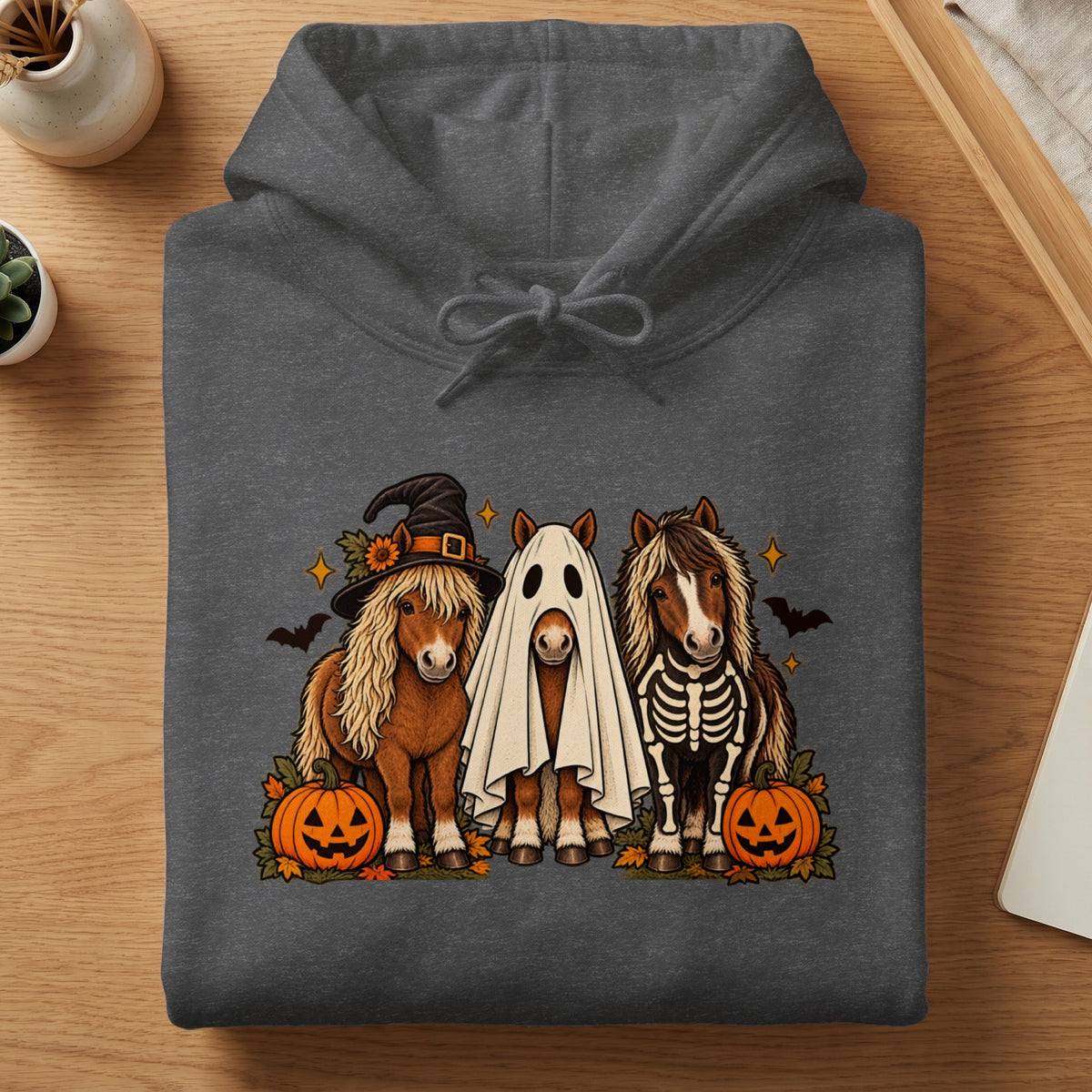 Three horses, one in a witch hat, one as a ghost, one in a skeleton costume, with pumpkins.