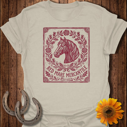 T-shirt with a red mare horse head logo surrounded by floral and thistle elements.