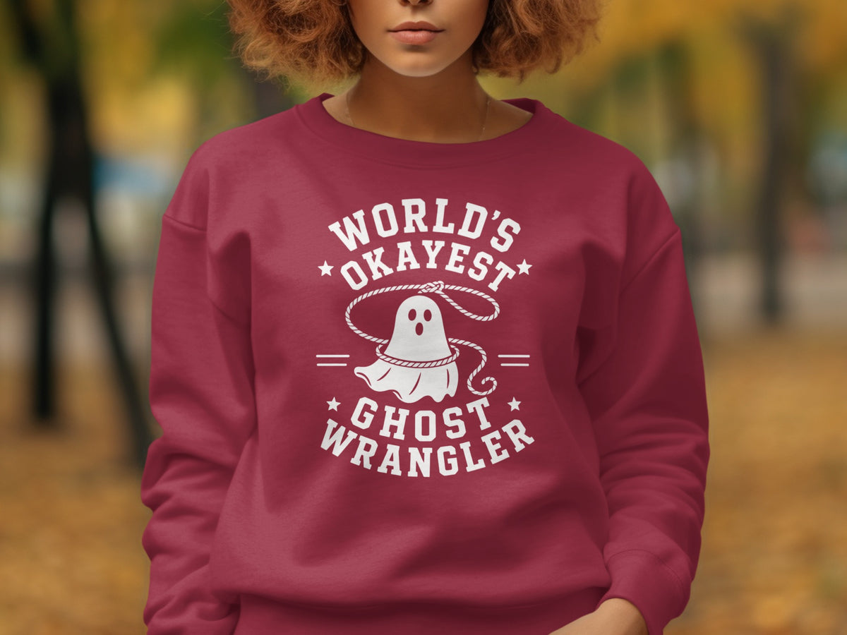 Burgundy sweatshirt with white text and ghost graphic: World's Okayest Ghost Wrangler.