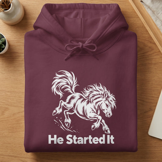 A folded maroon hoodie with a white graphic of a bucking horse and the text He Started It.