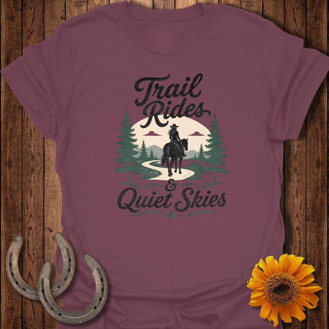 Maroon t-shirt graphic with horse rider, trees, mountains, and text "Trail Rides & Quiet Skies."