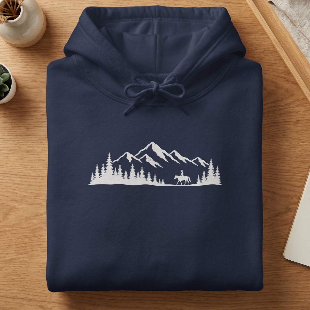 Navy hoodie with a white mountain, forest, and cowboy on horseback graphic.