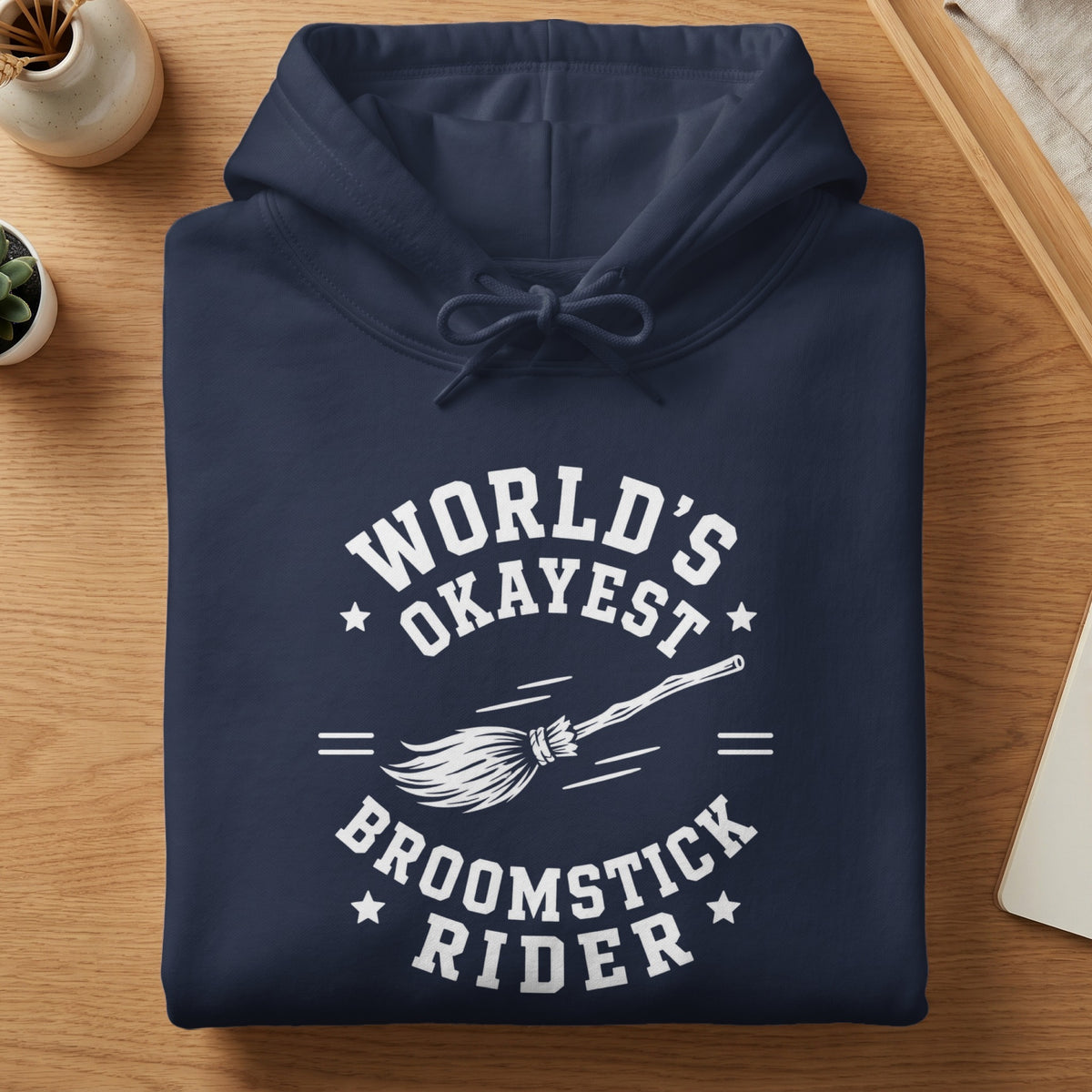 Navy hoodie with "World's Okayest Broomstick Rider" text and a broom.