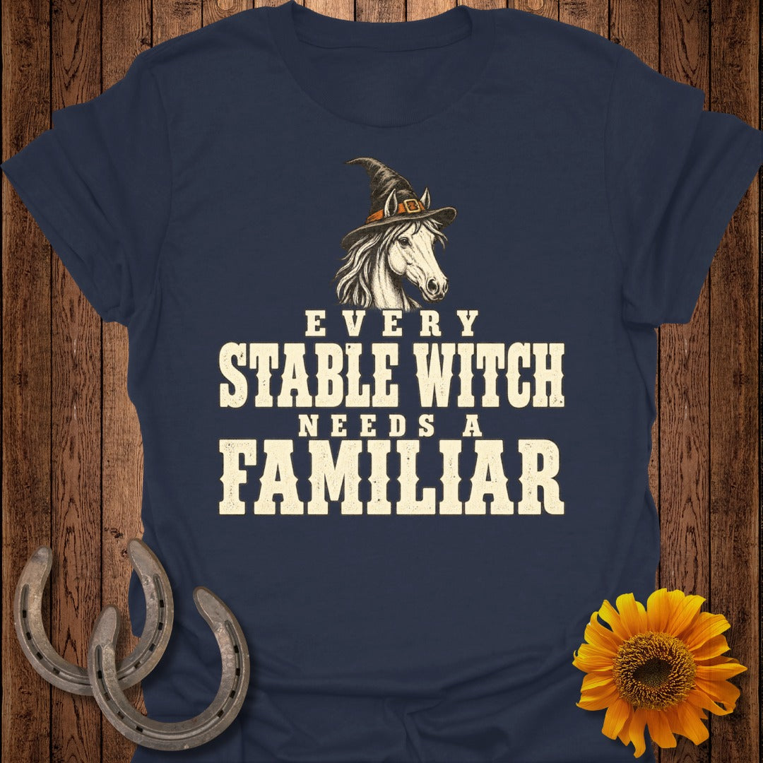 Dark blue t-shirt with text "Every Stable Witch Needs a Familiar" and horse graphic.