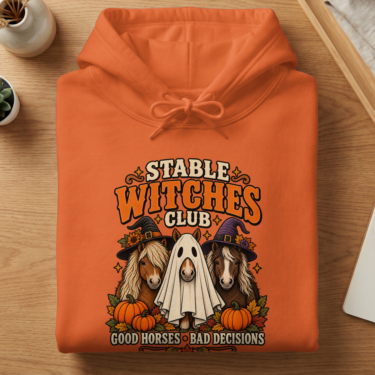 Orange hoodie with "Stable Witches Club" graphic and horses dressed for Halloween.
