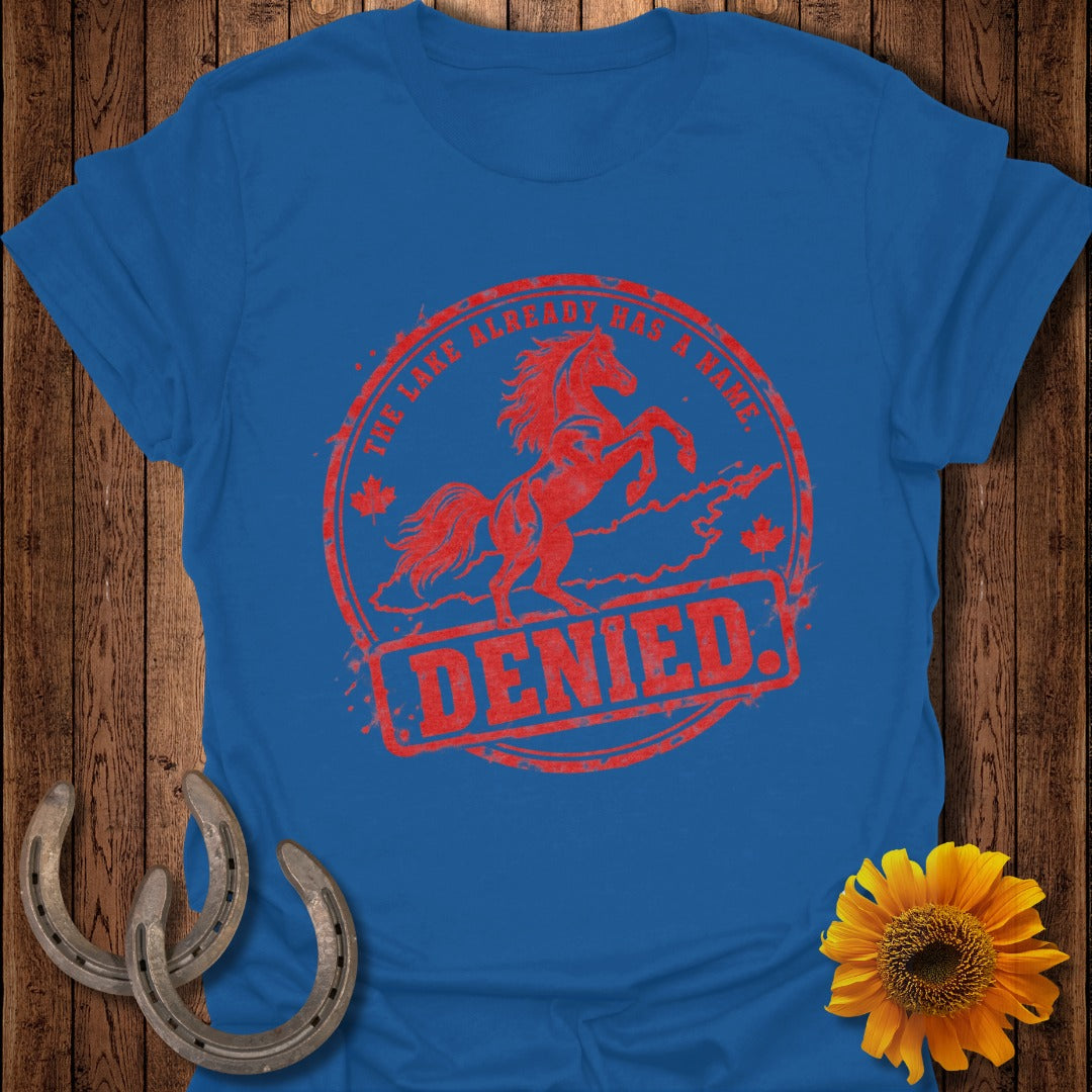 Red distressed stamp with horse and text "THE LAKE ALREADY HAS A NAME. DENIED." on blue shirt.