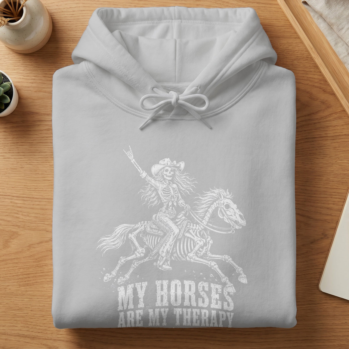 Grey hoodie with white graphic of a skeleton riding a horse and text "My Horses Are My Therapy."