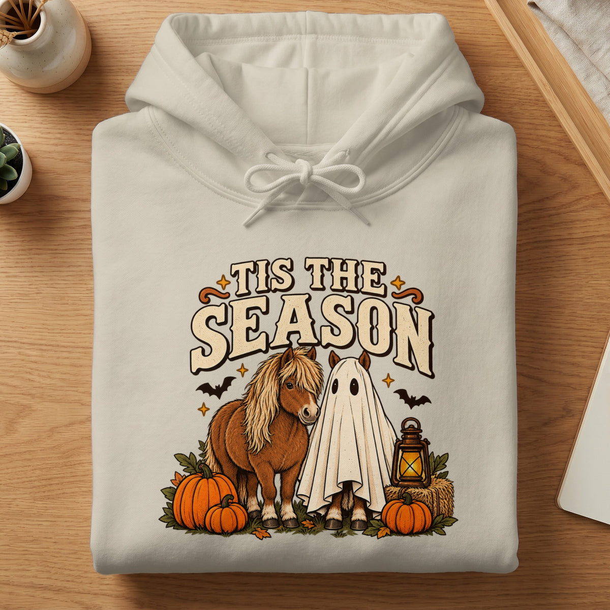 Cream hoodie with a "Tis The Season" graphic featuring horses, pumpkins, and bats.