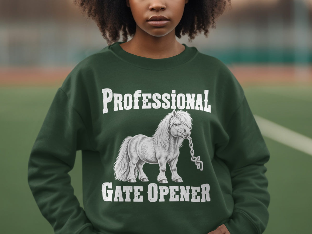 A person wearing a dark green crewneck sweatshirt featuring a graphic of a pony biting a chain with text reading Professional Gate Opener.