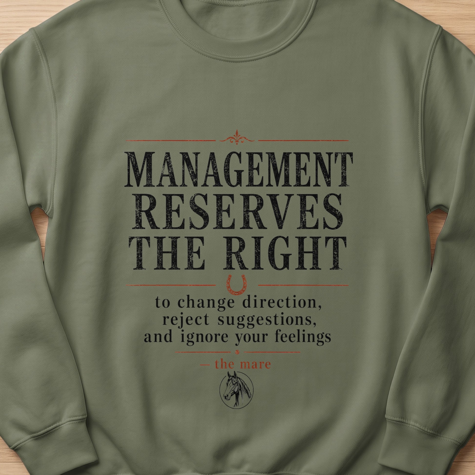 Olive green sweatshirt with text "MANAGEMENT RESERVES THE RIGHT to change direction, reject suggestions, and ignore your feelings — the mare".