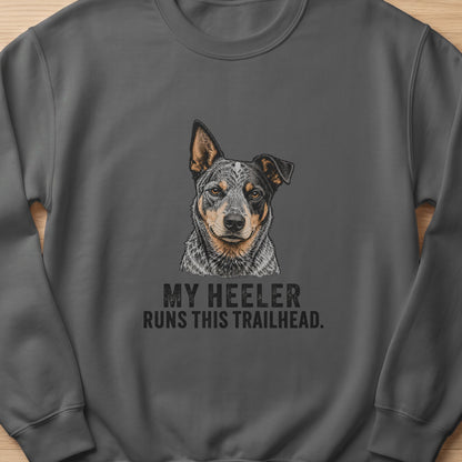 Dark grey sweatshirt with an illustration of a cattle dog and text that reads "My Heeler Runs This Trailhead."
