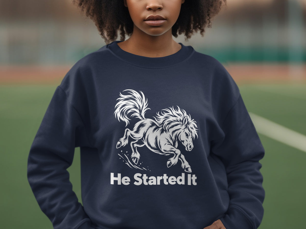 A person wears a dark blue crewneck sweatshirt featuring a white graphic of a running horse and the text He Started It.