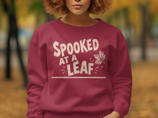 Maroon sweatshirt with "Spooked at a Leaf" text and leaf graphic.