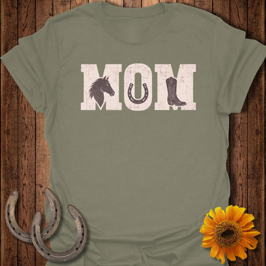 Distressed "MOM" text with horseshoe and cowboy boot graphics on a t-shirt.