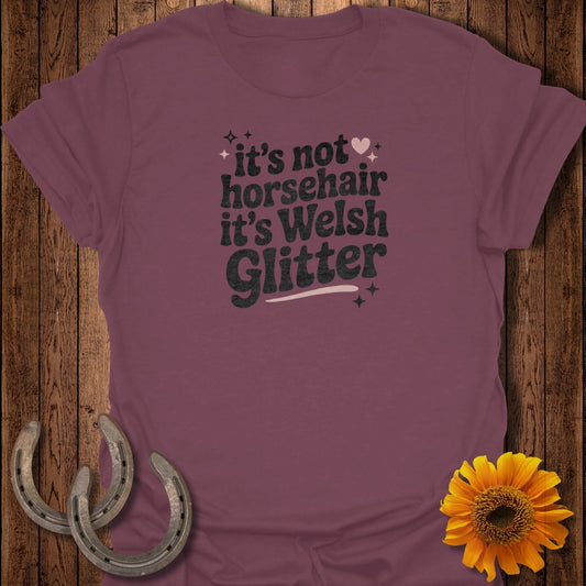 Maroon t-shirt with "it's not horsehair it's Welsh Glitter" text and horseshoe accents.
