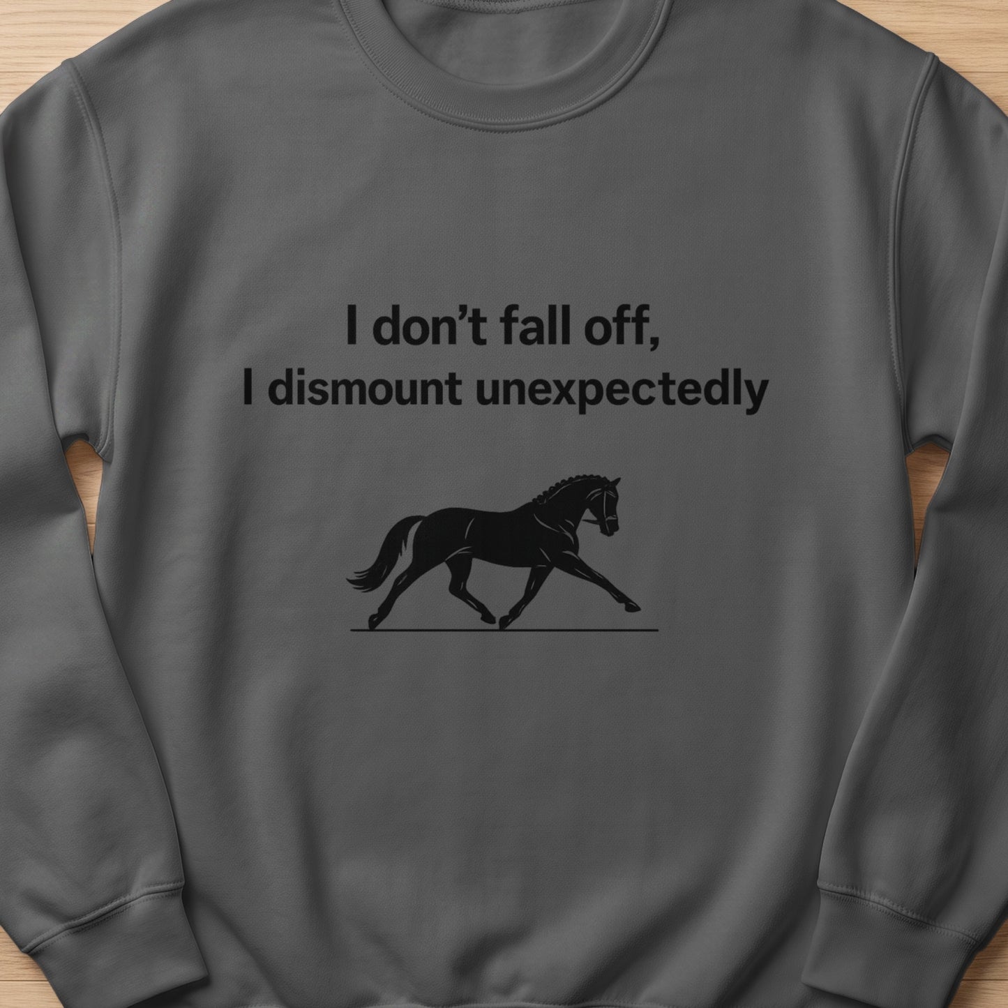 Dark gray sweatshirt with text "I don't fall off, I dismount unexpectedly" and a horse silhouette.