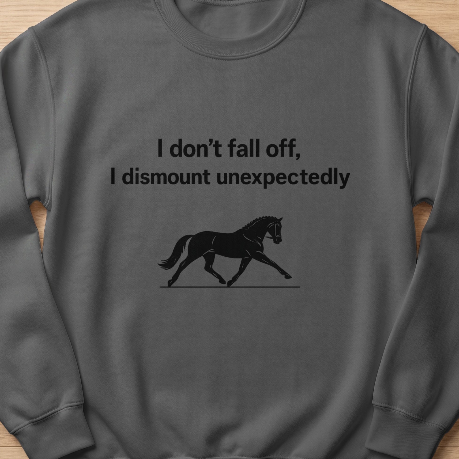 Dark gray sweatshirt with text "I don't fall off, I dismount unexpectedly" and a horse silhouette.