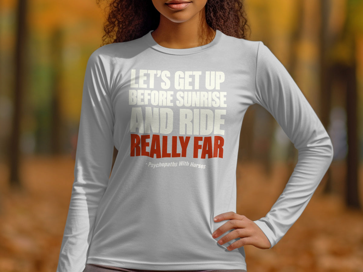 A person wearing a grey long-sleeve shirt with white and red text stating let's get up before sunrise and ride really far.