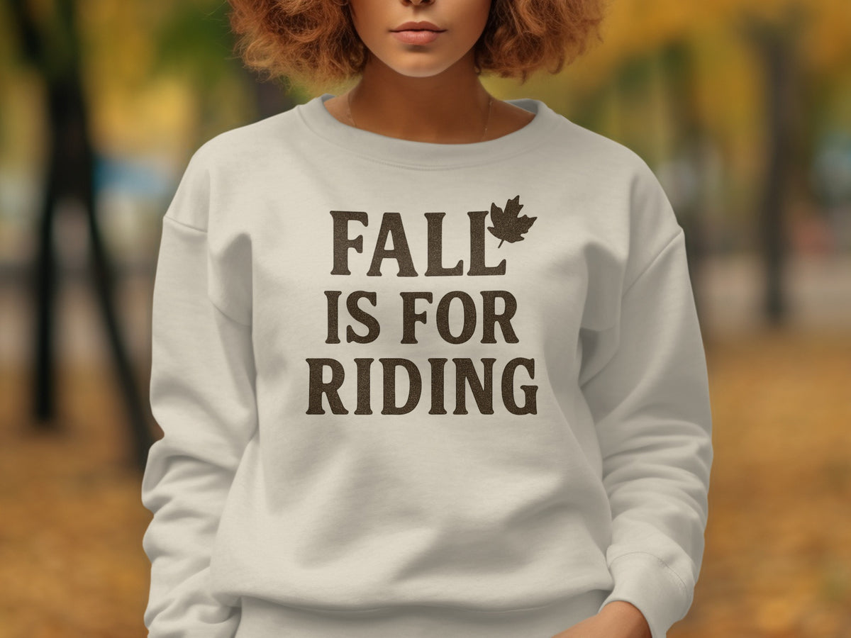 White sweatshirt with "FALL IS FOR RIDING" text and maple leaf graphic.