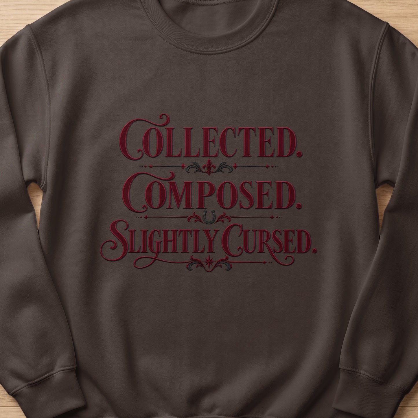 Brown sweatshirt with red text "Collected. Composed. Slightly Cursed."
