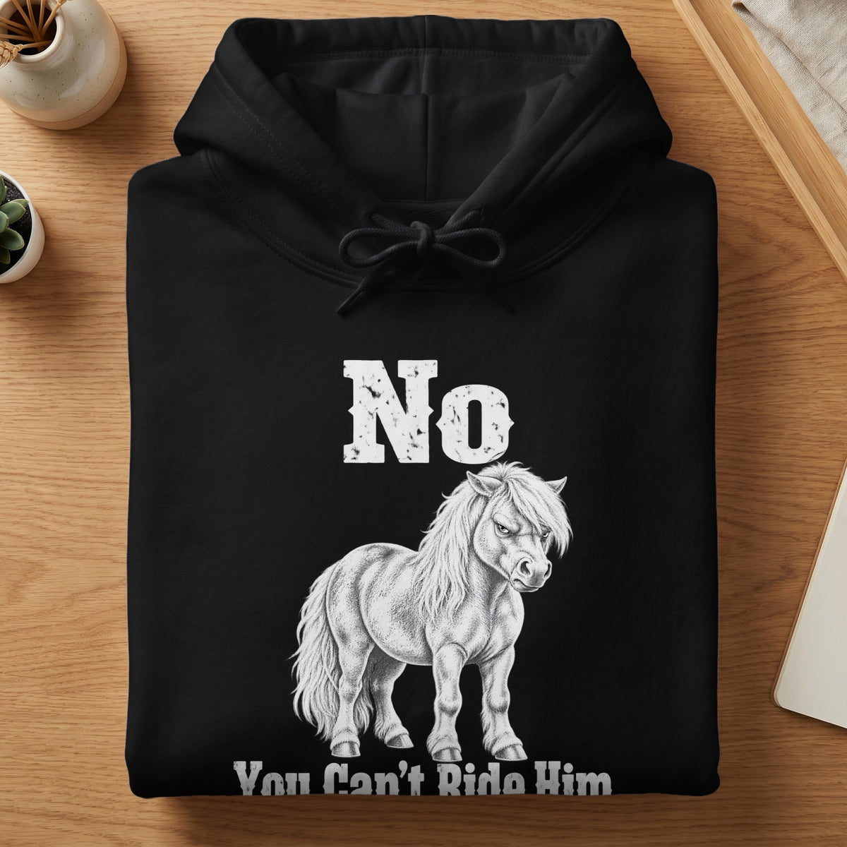 A folded black hooded sweatshirt featuring a white graphic of an angry pony with the text No You Can't Ride Him.
