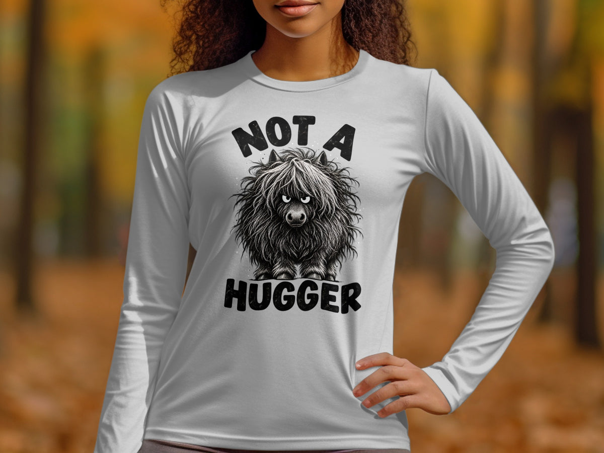 White long-sleeve shirt with a black graphic of a fluffy highland cow and text "NOT A HUGGER".
