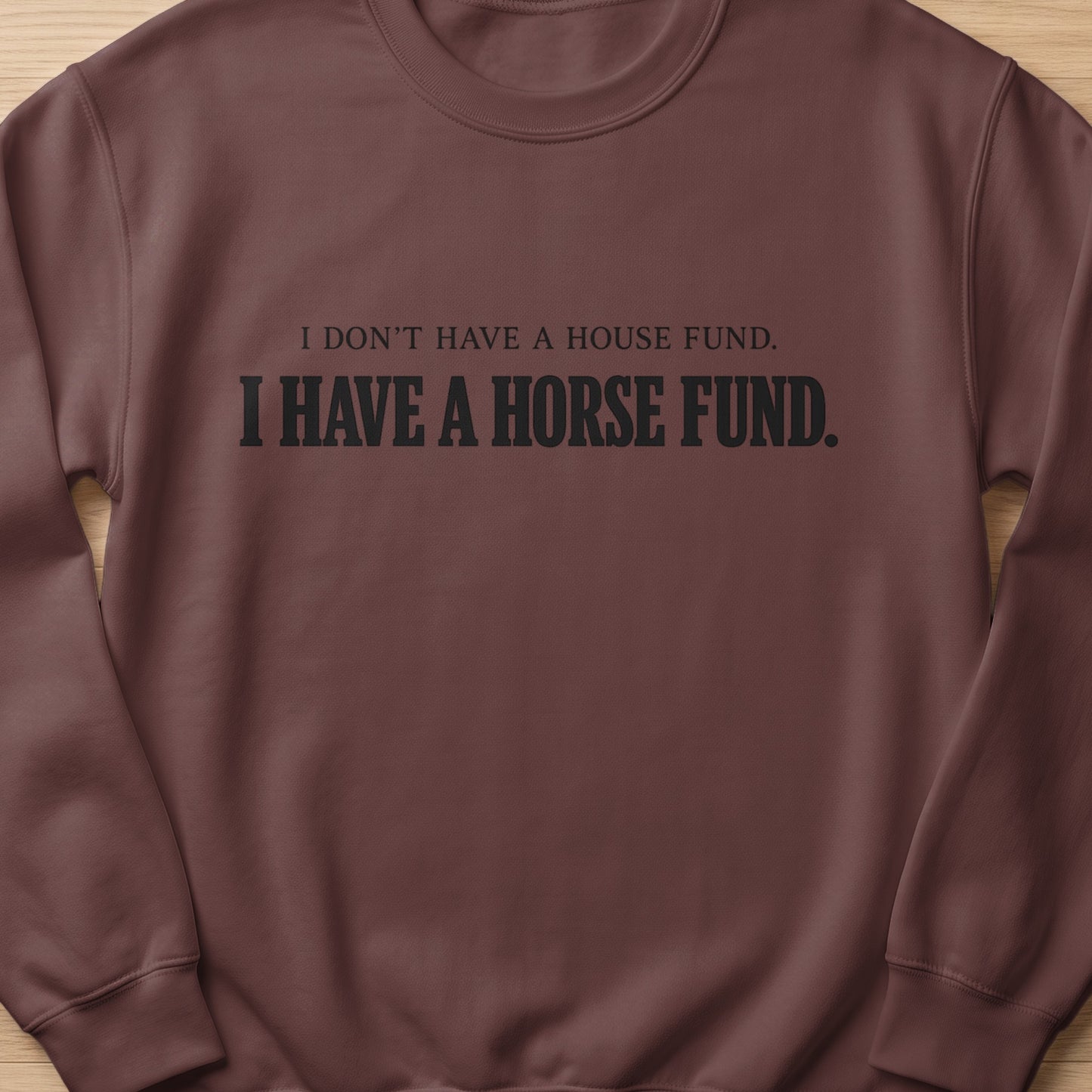 Brown crewneck sweatshirt with black text that reads "I DON'T HAVE A HOUSE FUND. I HAVE A HORSE FUND."